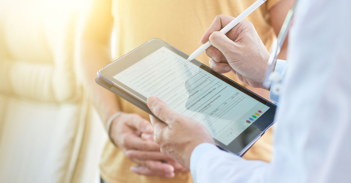 Un medico tiene in mano un tablet e compila con un pennino un modulo digitale. Davanti a lui una paziente. Si intuisce che il medico sta raccogliendo l'anamnesi e registrerà i dati direttamente sulla CCE, dove saranno accessibili agli operatori interessati. Questo è solo un esempio dei vantaggi apportati dalla CCE a cliniche e ospedali.